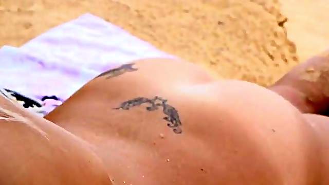 Naked blonde cutie relaxes on a private beach